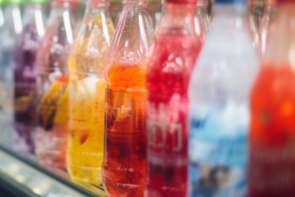 Brightly colored sodas in glass bottles in a refrigerated display